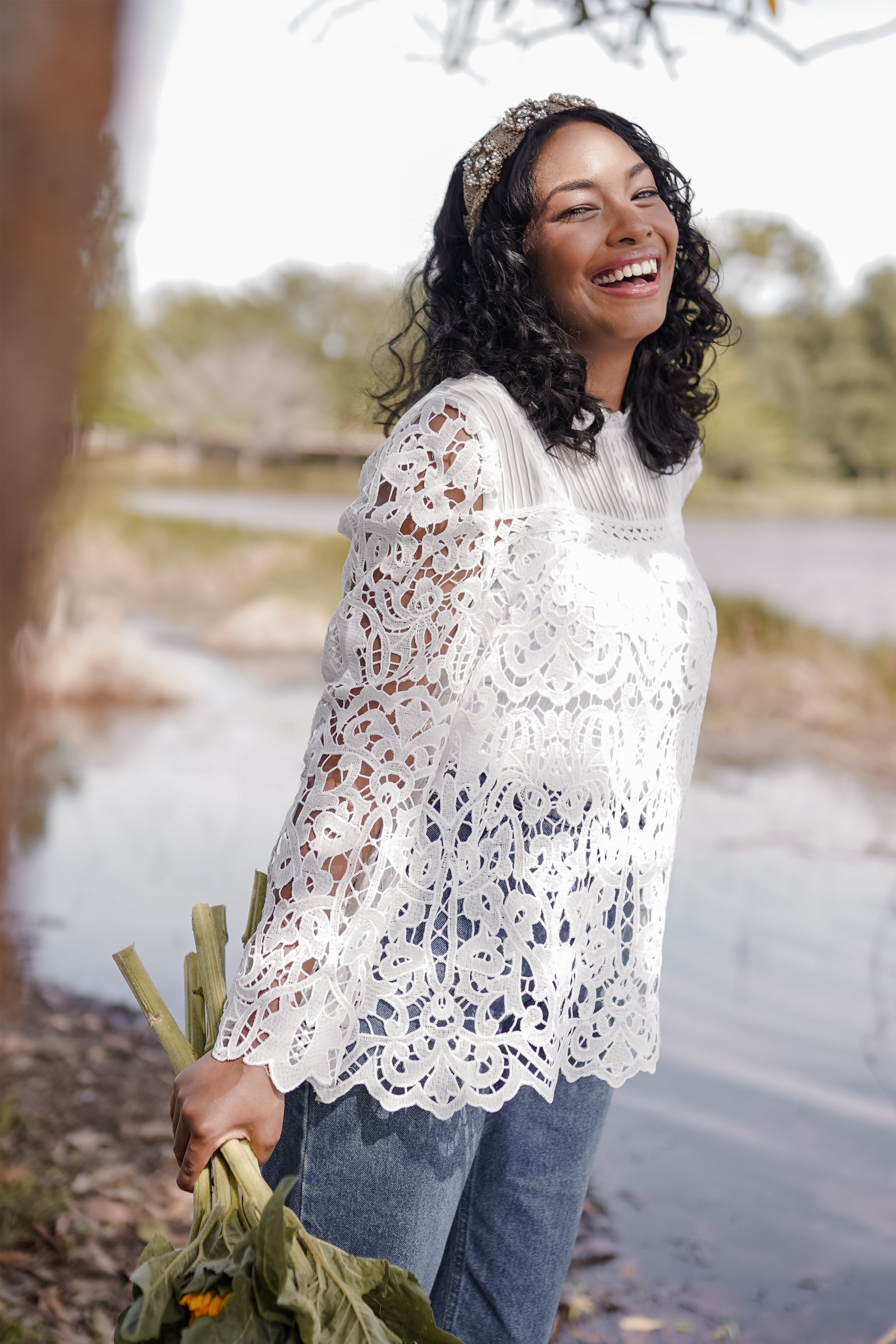 Female model in high quality laced top made by petit moi. Posing by the lake