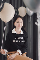 Female model holding a balloon and wearing high quality black sweater made by petit moi