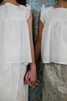 Sisters wearing matching tops and holding hands to pose for the camera
