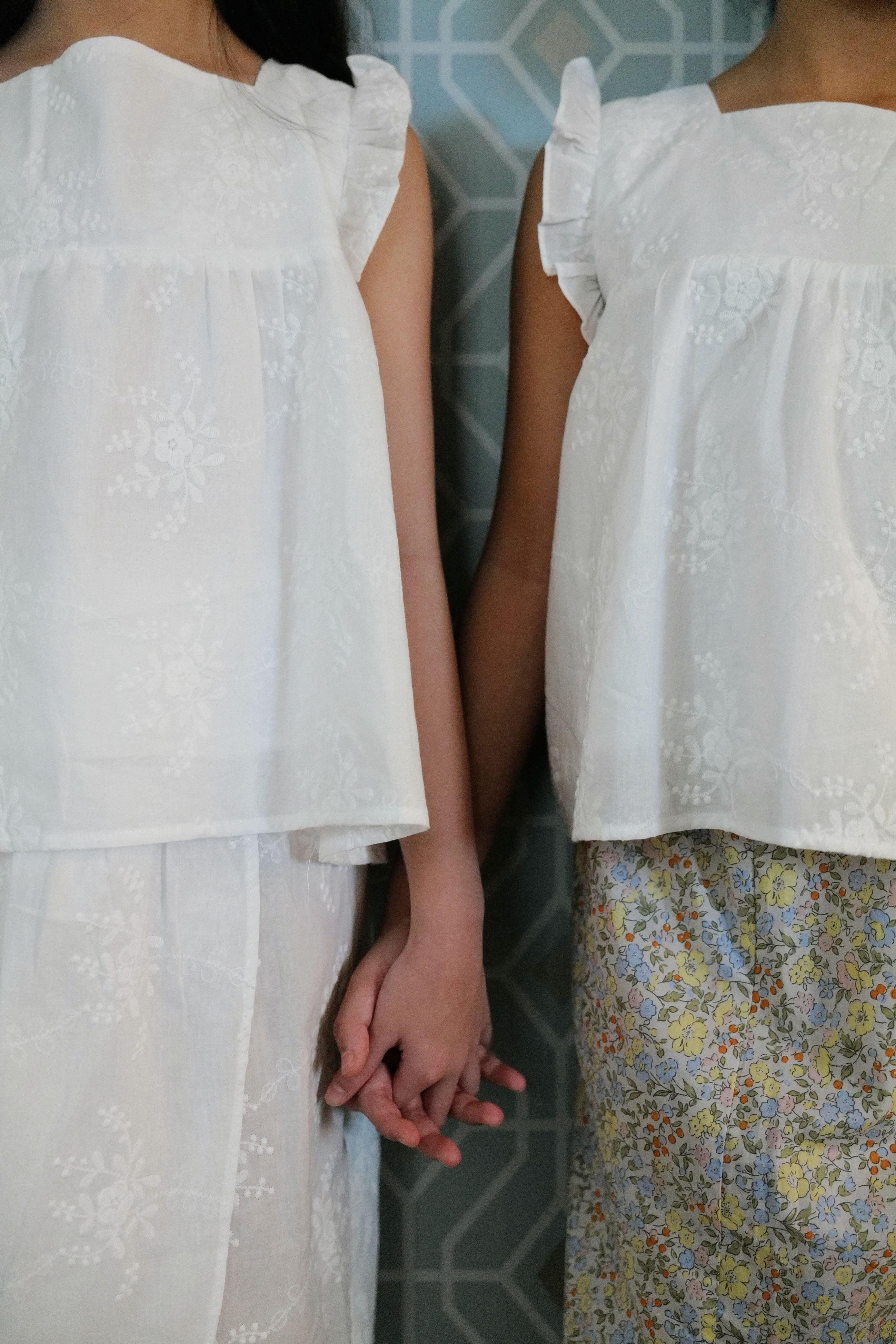 Sisters wearing matching tops and holding hands to pose for the camera