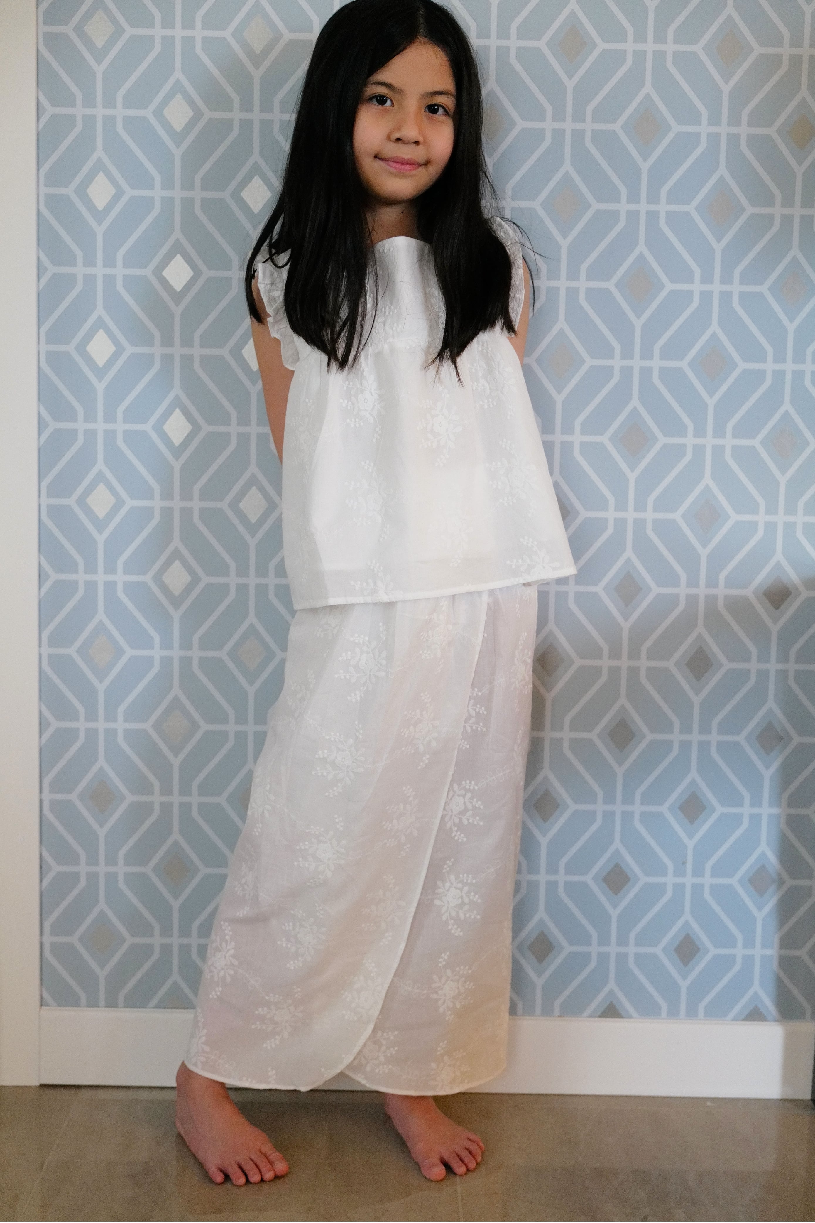Little girl wearing white dress with a blue background