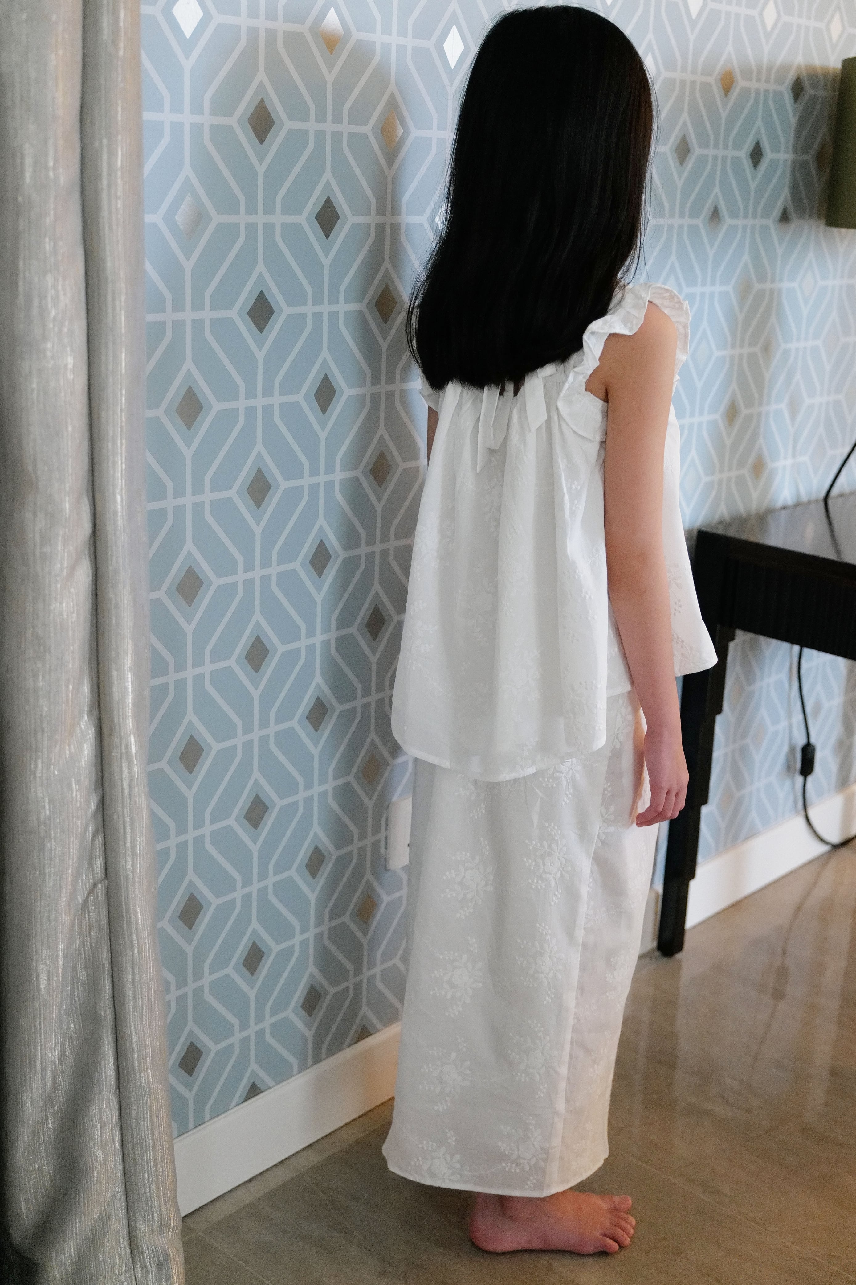 Little girl wearing white dress and facing opposite of the camera