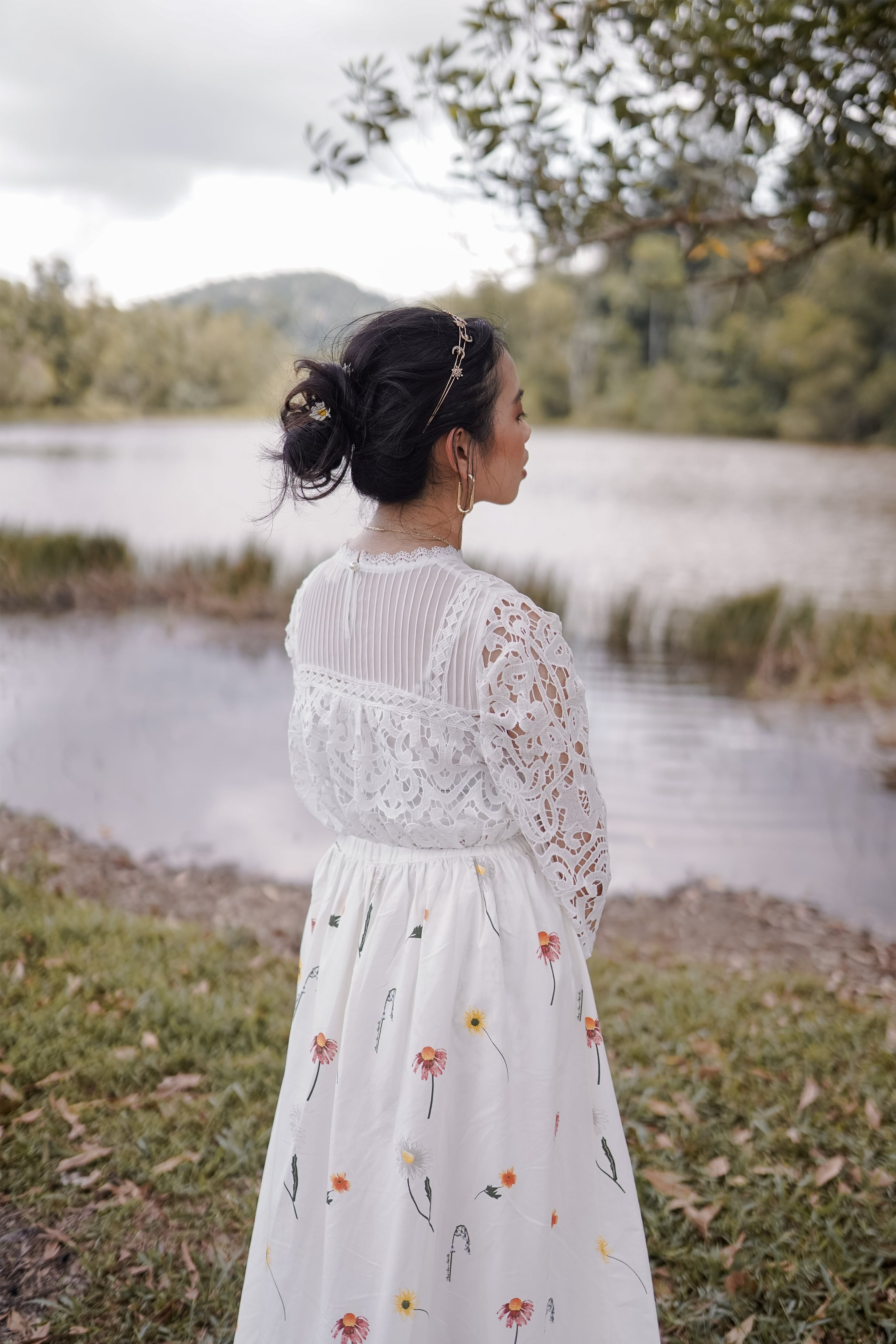 Back shot of female model posing by the lake. wearing a high quality top made by petit moi