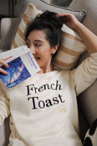 Woman in high quality sweater holding a book and lying down on a couch