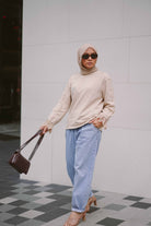 Female model posing in a beige jumper designed by petit moi