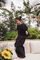 little girl in black baju kurung made by petit moi jumping on the sofa