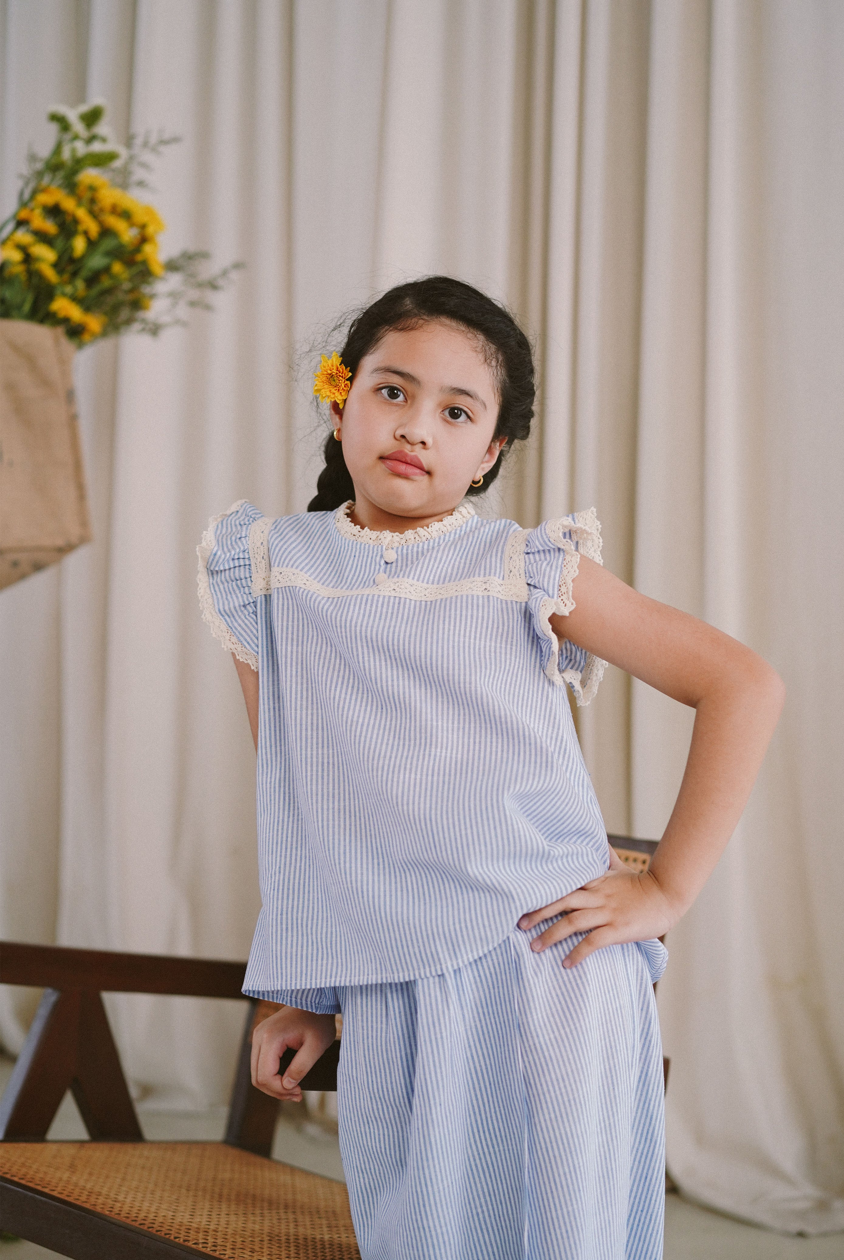 little girl in light blue baju kurung made by petit moi. posing for the camera