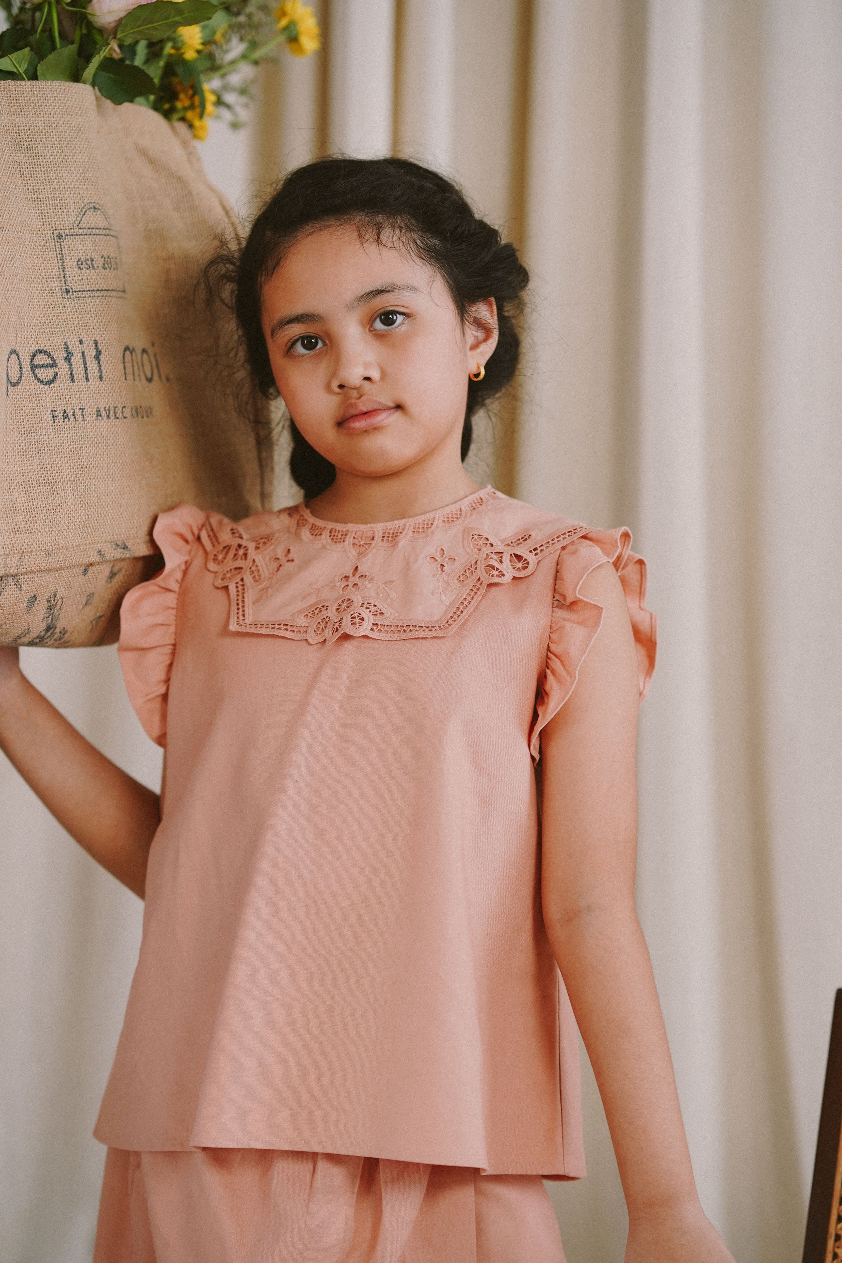 Little girl posing for the camera in high quality modest clothes made by petit moi