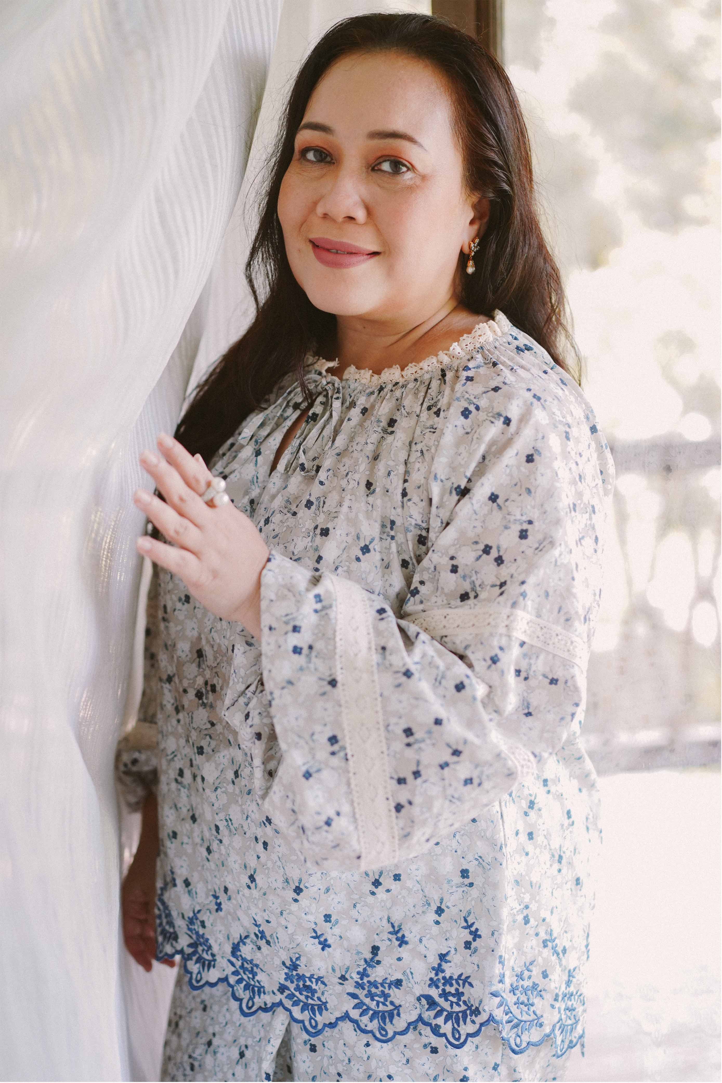 mature woman in blue floral baju kurung designed by petit moi