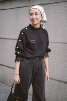 Female model happily posing for the camera in her new black jumper designed by petit moi