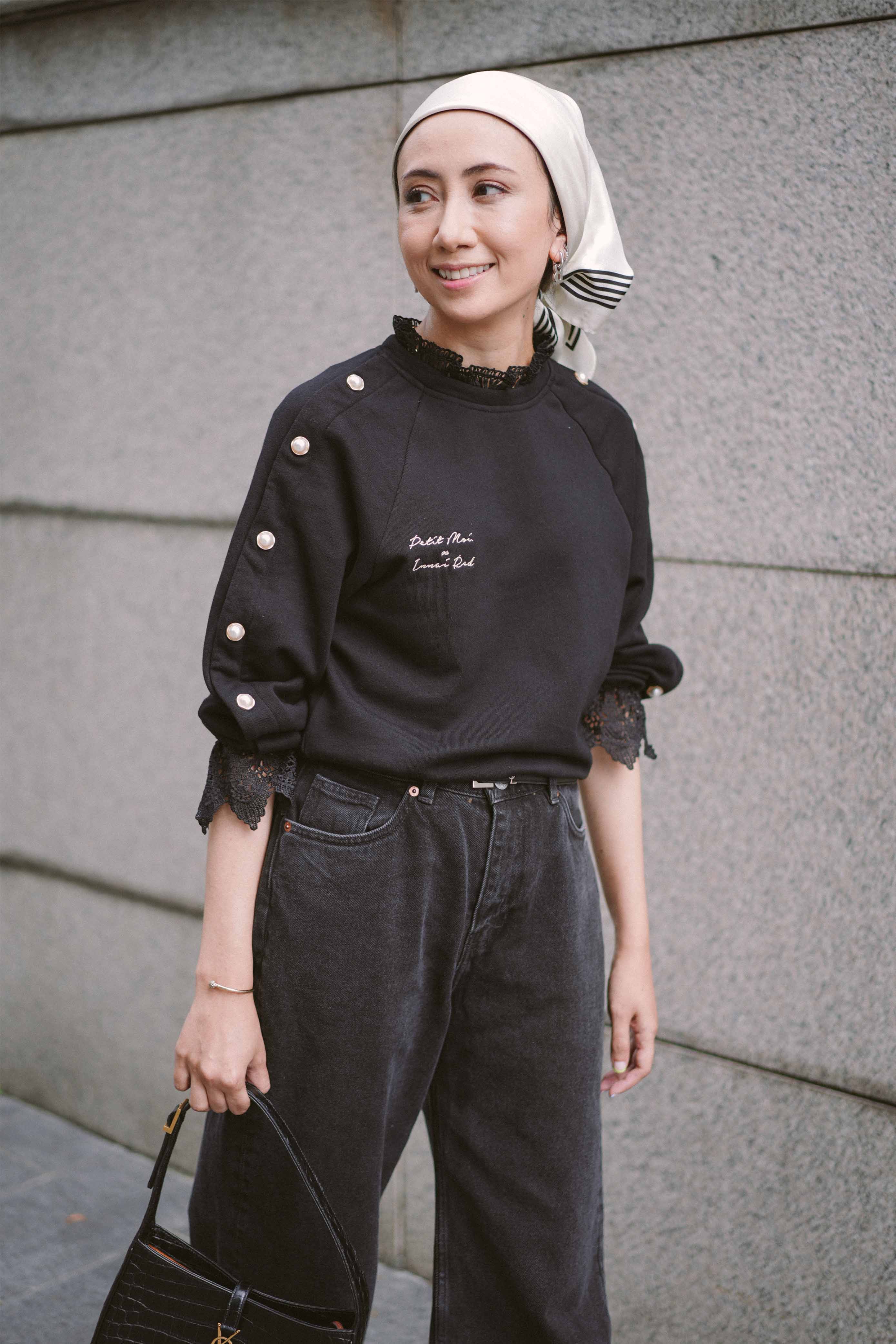 Female model happily posing for the camera in her new black jumper designed by petit moi