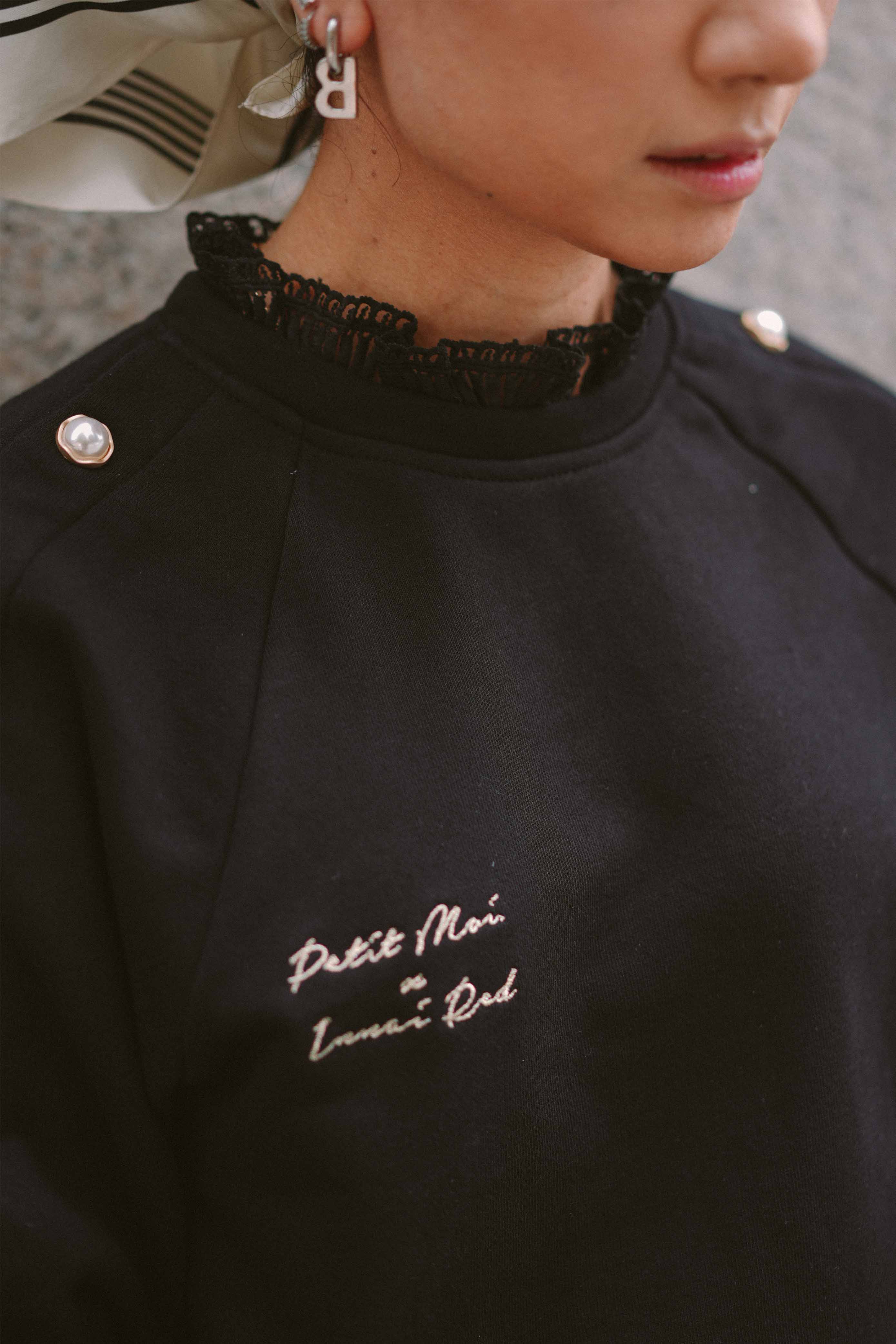 Closeup shot of female model wearing her favourite black jumper by petit moi
