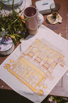 petit moi yellow bingka tea towel and cup on table