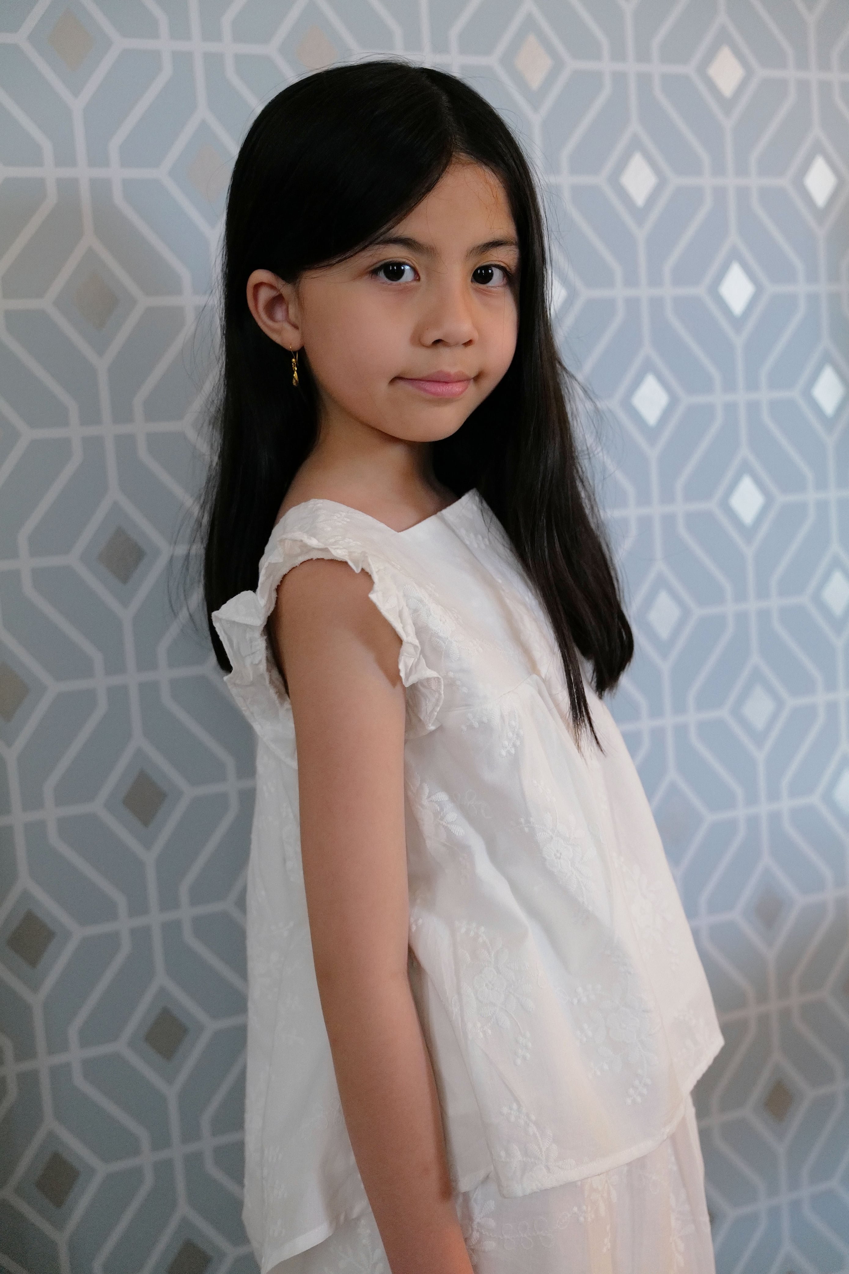 Little girl wearing white dress and posing for the camera