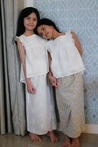 Sisters wearing matching white tops designed by petit moi