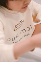 closeup shot of little kid wearing high quality sweater made by petit moi