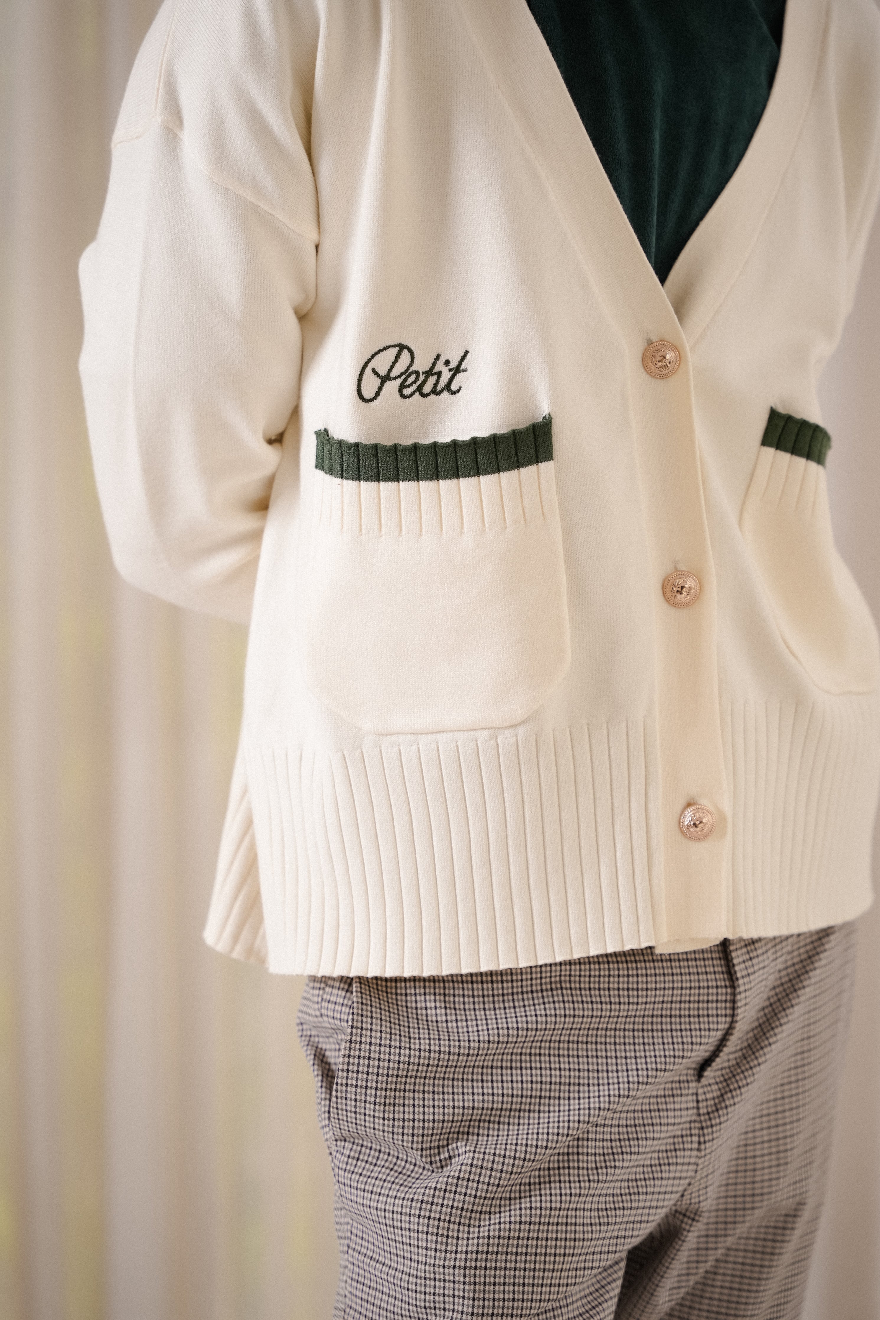 front closeup shot of male model wearing high quality white and forest green cardigan made by petit moi