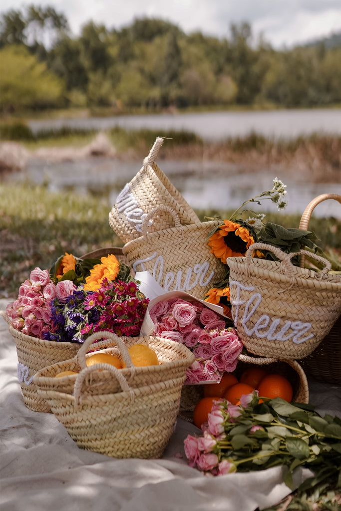 High quality handmade woven bags by petit moi. arranged with flowers by the lake for a picnic