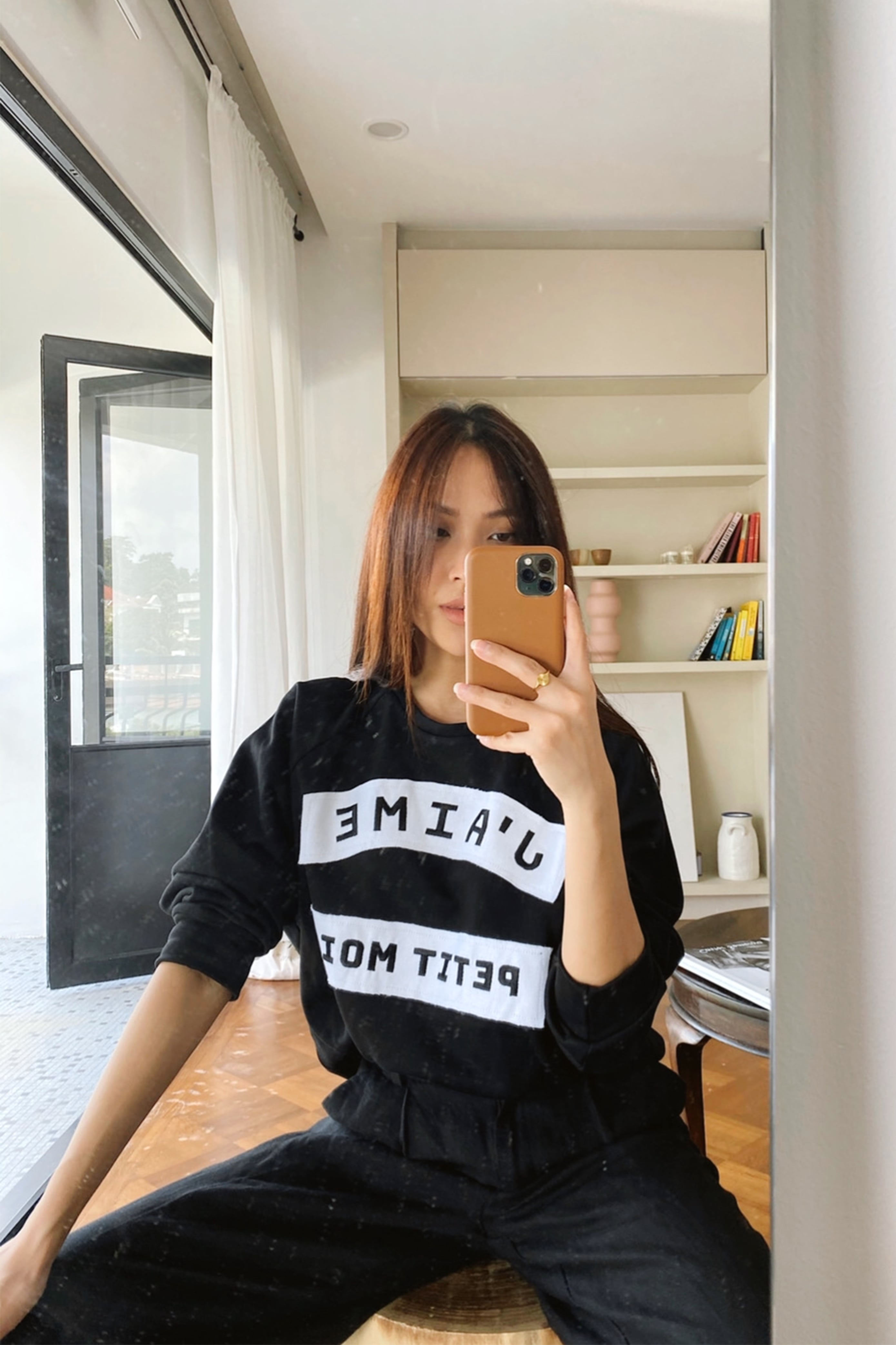 Female model in high quality black sweater made by petit moi. taking a mirror selfie