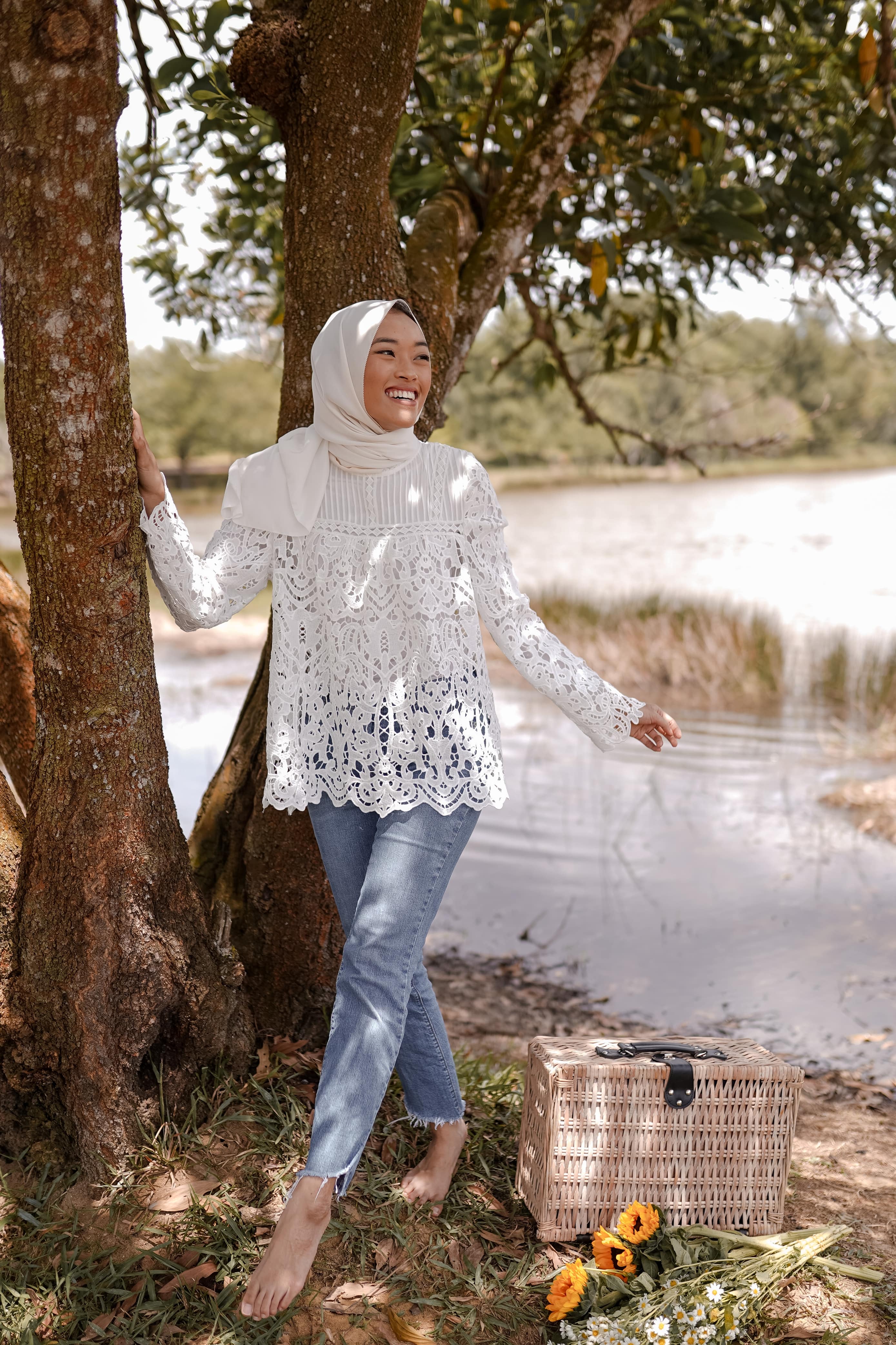 Female malaysian model wearing a high quality laced top made by petit moi. posing by the tree and lake