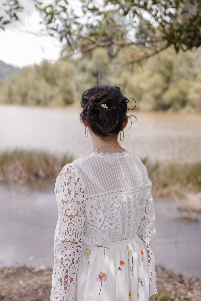 Back shot of female model posing by the lake. Wearing a high quality top made by petit moi