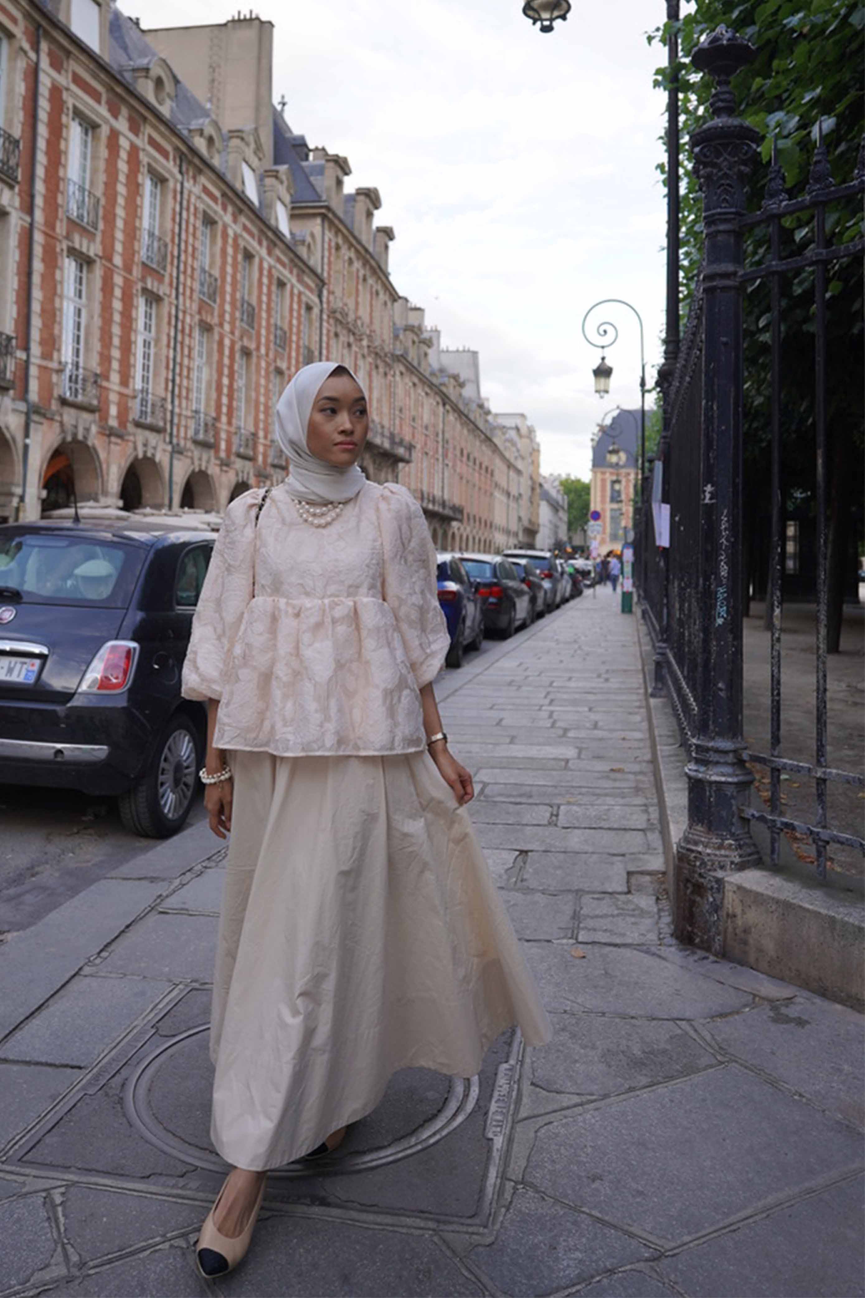 Female model walking down the streets of Paris. Wearing a french inspired top made by petit moi
