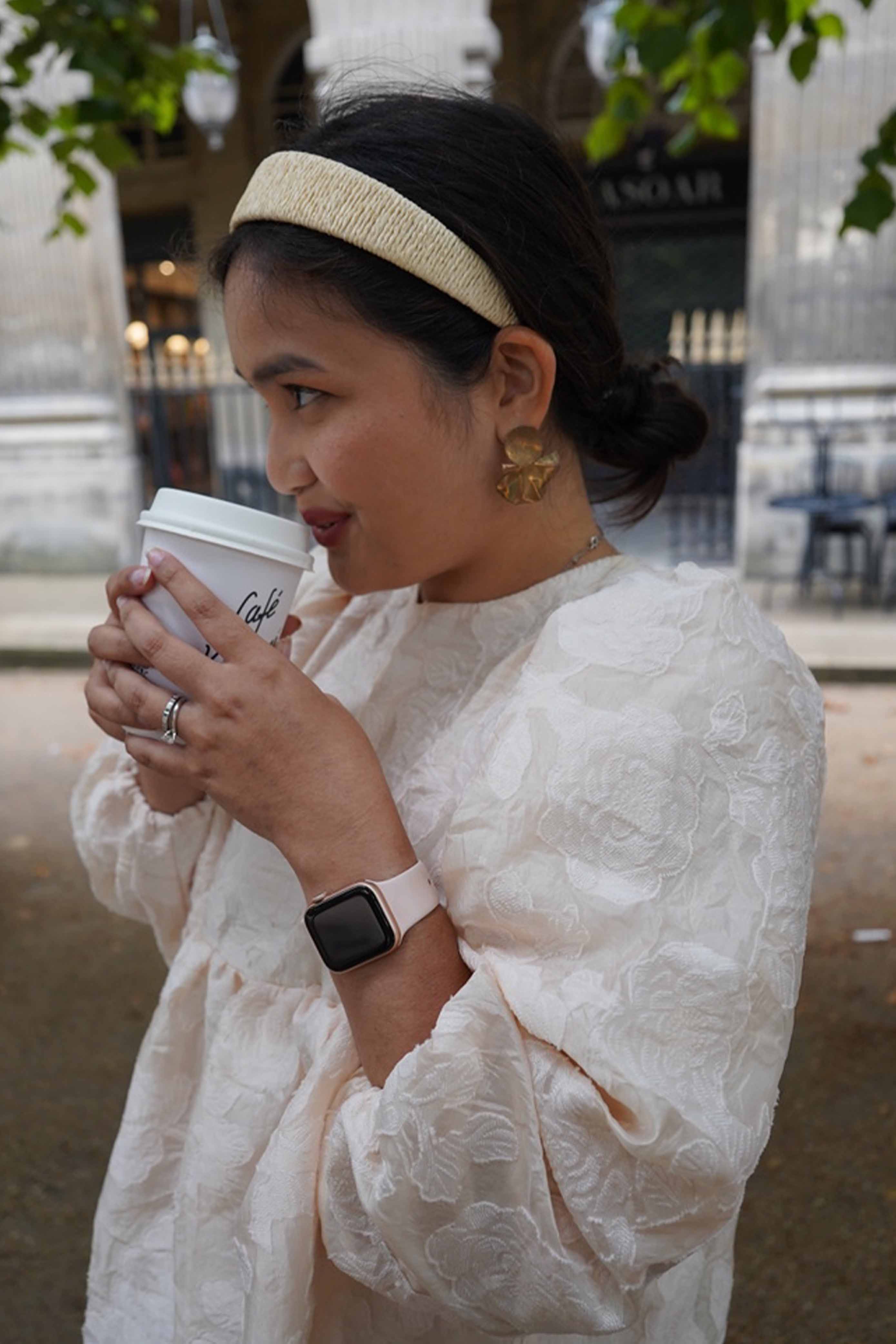 Female model sipping on her coffee in paris. while wearing high quality french inspired top made by petit moi