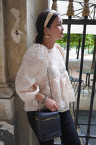 Female model wearing a high quality french inspired top by petit moi. Leaning on the wall while looking the other way around