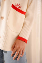 Closeup shot of sleeve of white and red cardigan made by petit moi