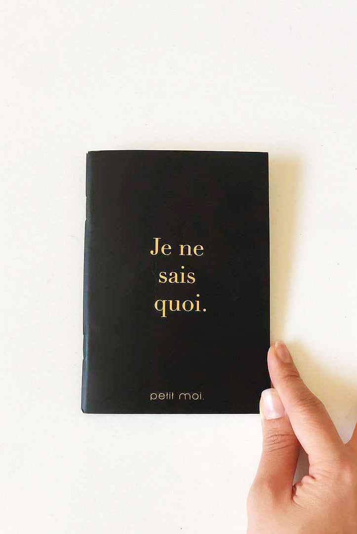 High quality black notebook by petit moi. Closeup shot on a white table
