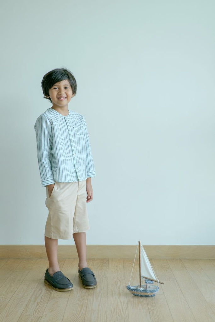 Little boy wearing a  high-quality striped blue shirt . Made by petit moi