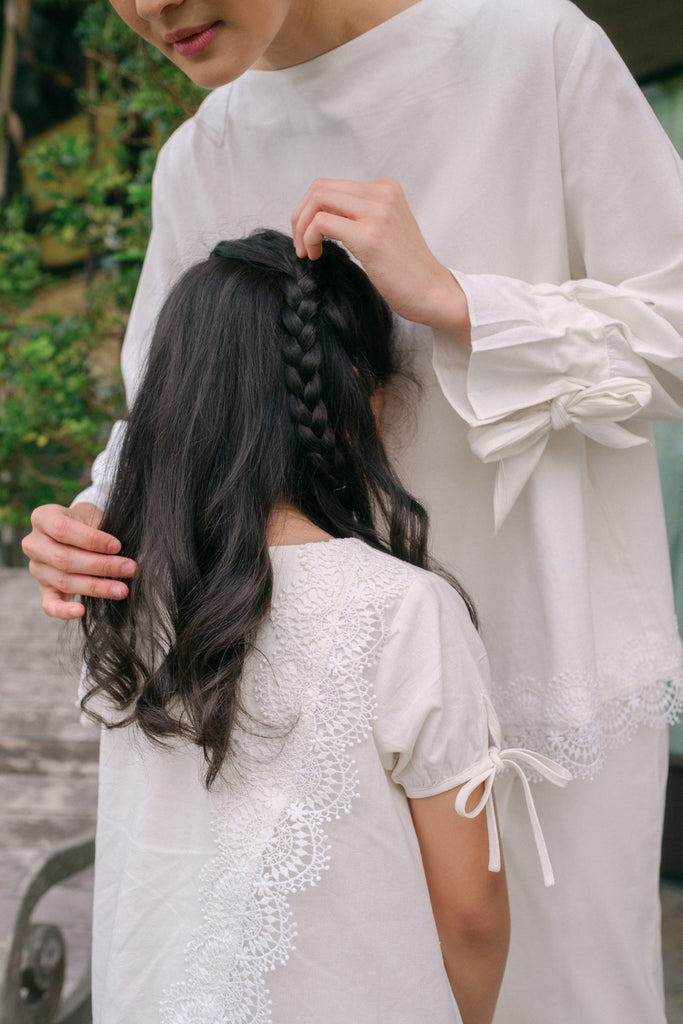 Mother fixing her daughters hair during hari raya