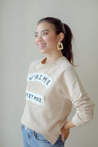 Side shot of female model wearing high quality beige sweater made by petit moi