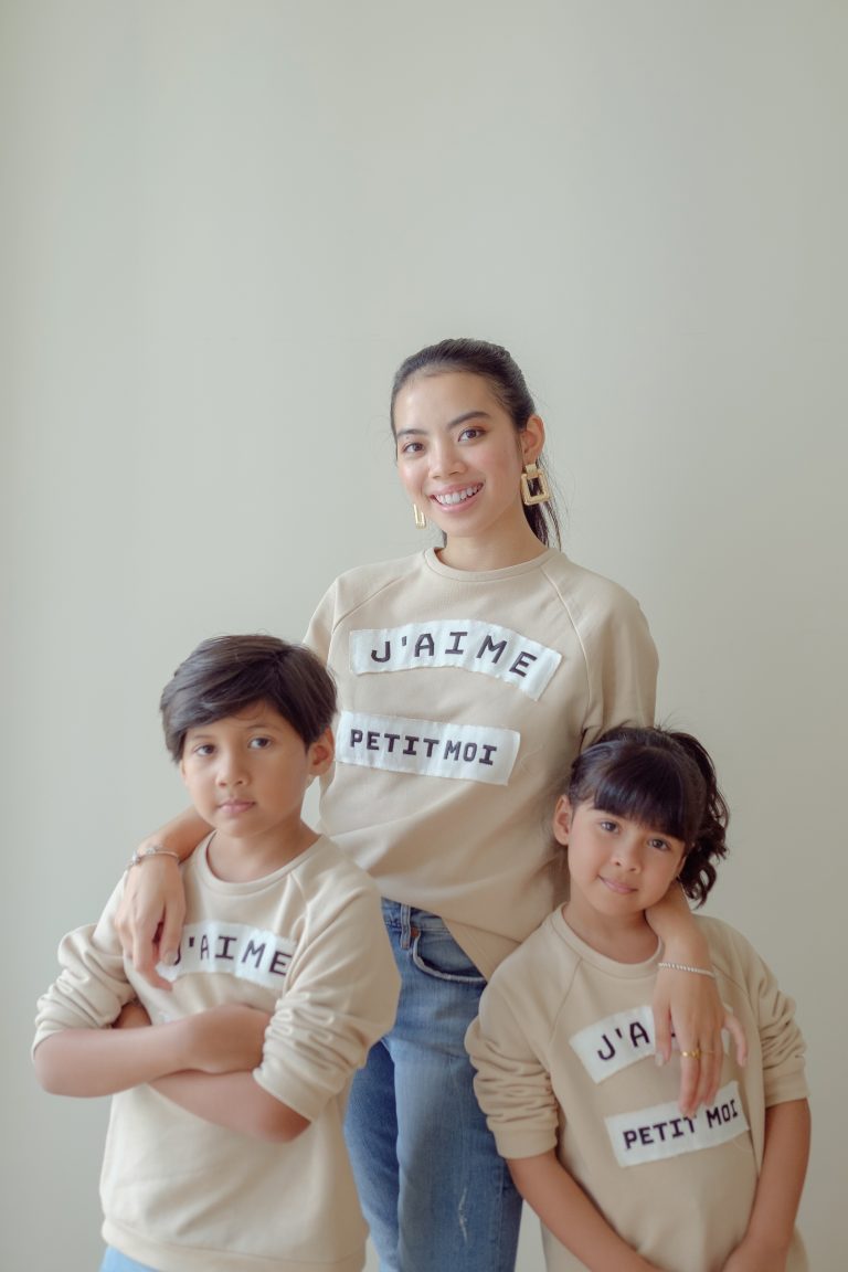 Mother and her kids happily wearing matching sweaters made by petit moi and posing for the camera
