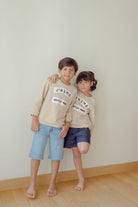 Brother and sister wearing high quality matching jumpers made by petit moi. Leaning on each other and posing for the camera