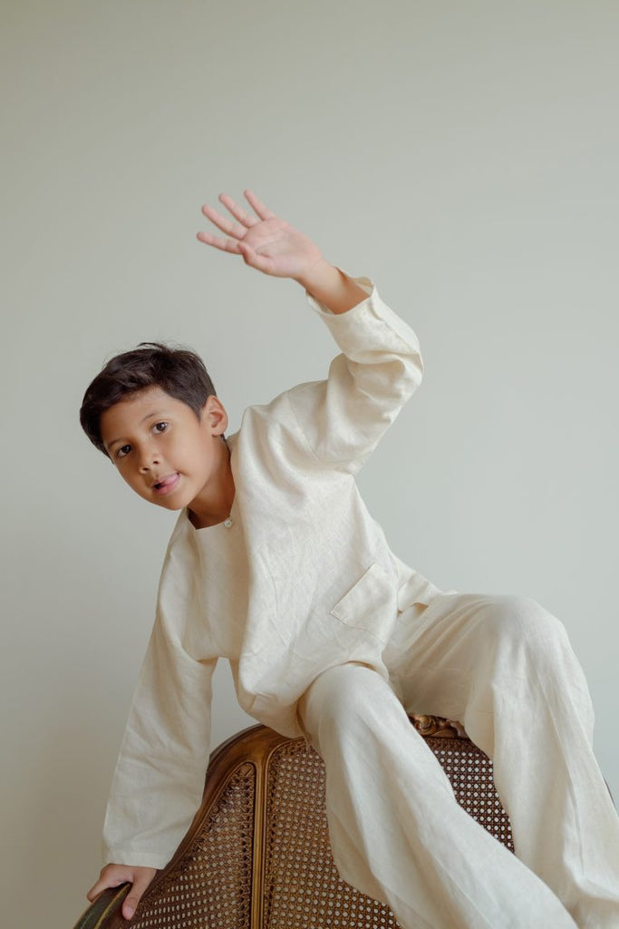 boy in white kurta sitting down on chair