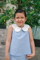 little girl smiling in her favourite light blue outfit by Petit Moi