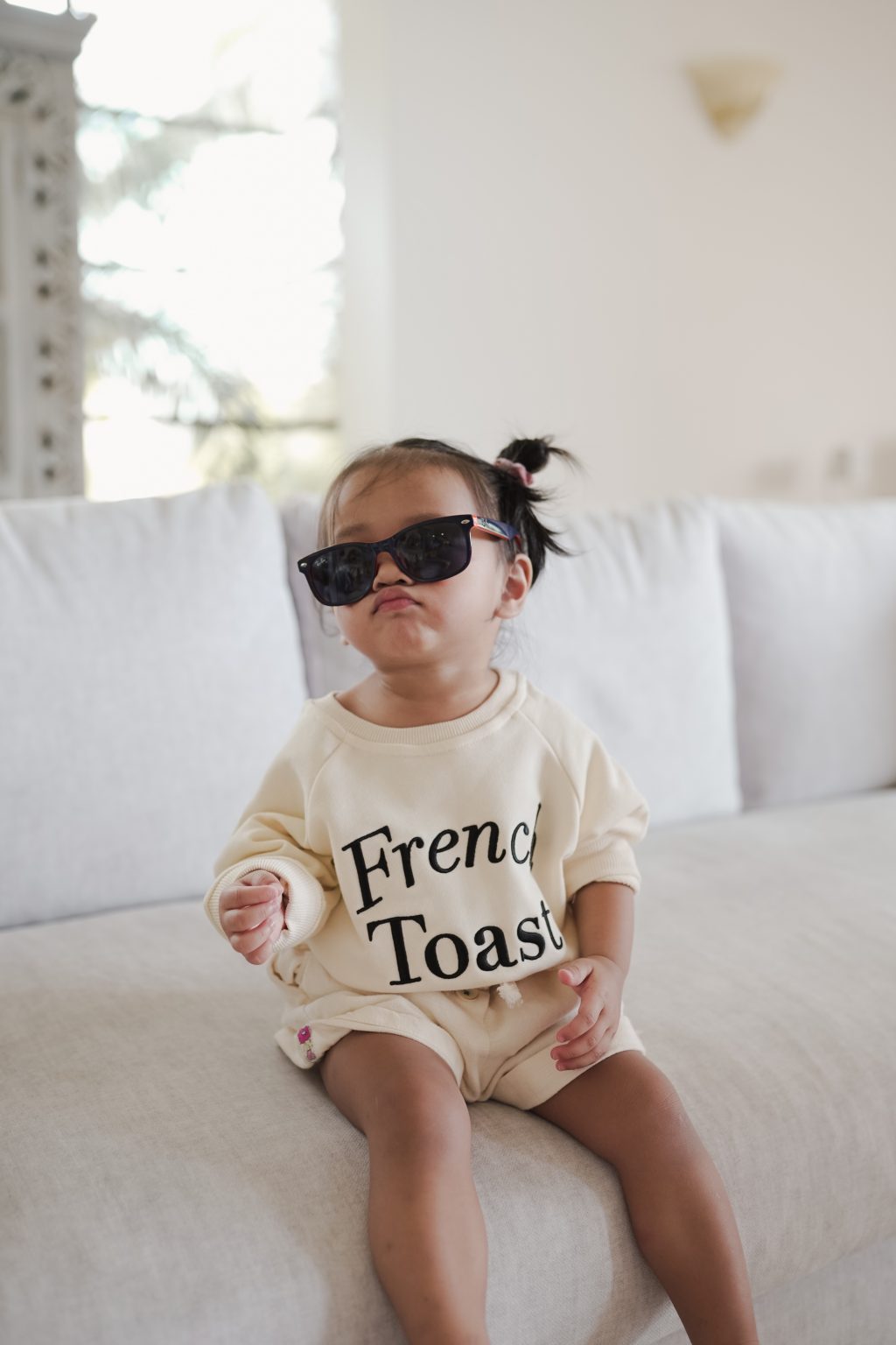 Little girl posing in sunglasses and high quality sweater made by petit moi