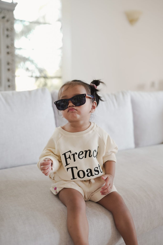 Little girl posing in sunglasses and high quality sweater made by petit moi