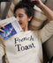Woman in high quality sweater holding a book and lying down on a couch