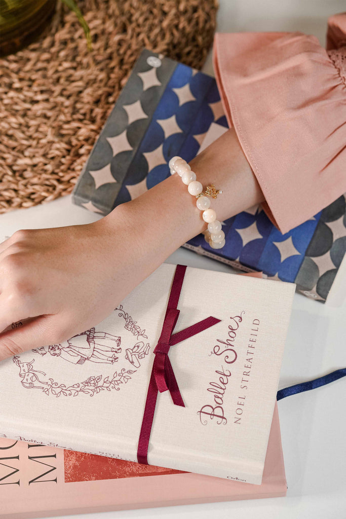 wearing petit moi bracelet on table with books 