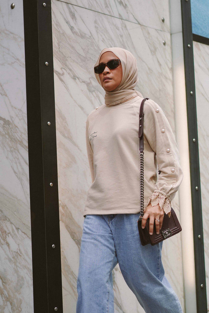 Female model walking around the city in a beige jumper
