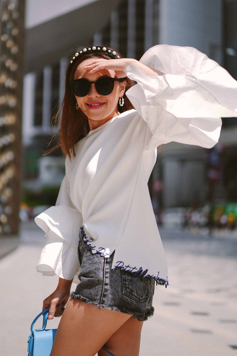 female model in white blouse by petit moi posing for the camera