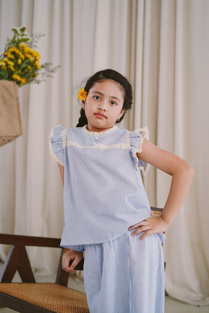 little girl in light blue baju kurung made by petit moi. posing for the camera