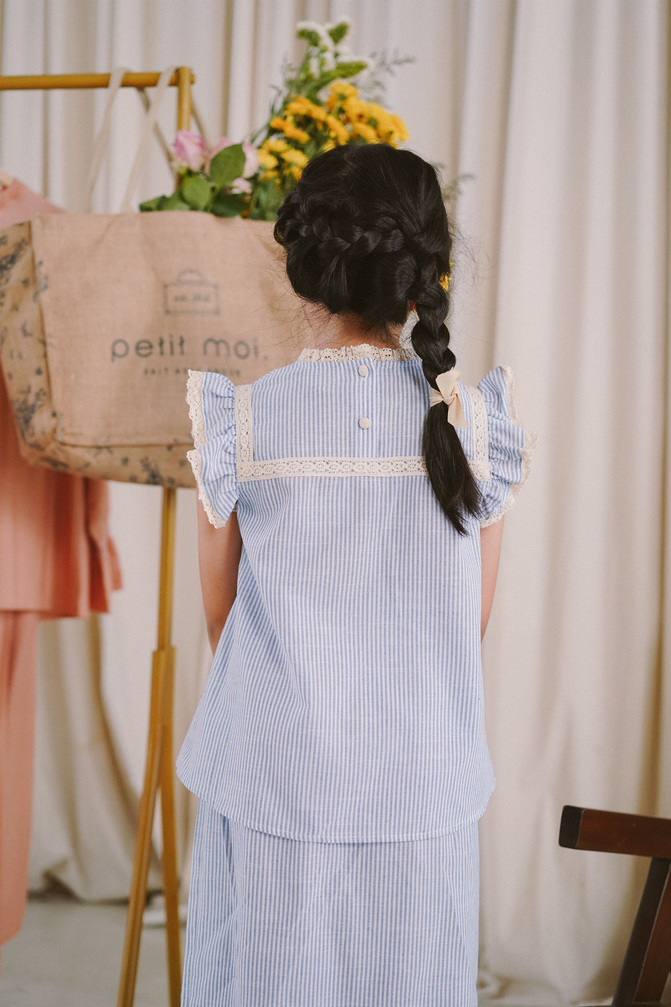 back shot of little girl in blue and white striped baju kurung made by petit moi