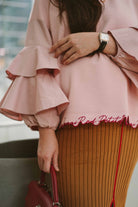 female model in pink ruffled blouse by petit moi