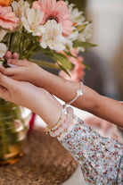 Mother and daughter wearing their matching bracelets while admiring a flower