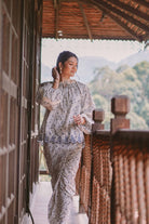 female model posing in wooden house wearing high quality floral baju kurung made by petit moi