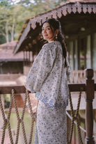 Female model wearing blue floral baju kurung turning head to the side
