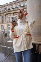 female model holding her phone and wearing a high quality cardigan made by petit moi